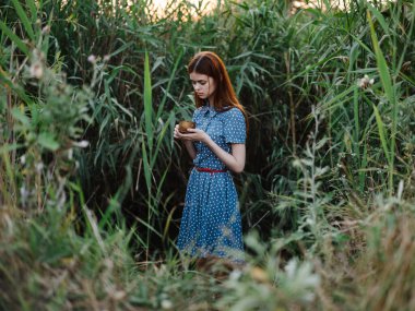 Akşamları yeşil çimlerin yanında mavi elbiseli bir kadın.