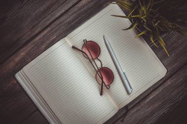 Not defteri bardakları ve saksıda bir çiçek Tahta bir masanın üstünde kalem ofisi