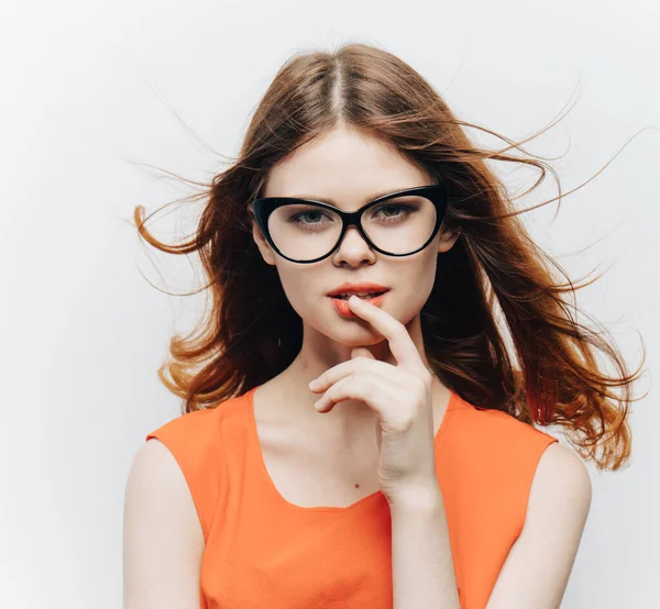 Mulher bonita em vestido de laranja e óculos em um fundo leve vista cortada — Fotografia de Stock