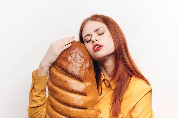 Mulher beijando pão no fundo claro e amarelo produto de farinha camisa vista cortada — Fotografia de Stock