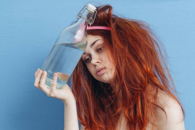 Uyku maskesi takmış, akşamdan kalma içki şişesi elinde.