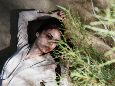 Kadın doğada ve yerde yatıyor ve yeşil yapraklar dinleniyor.