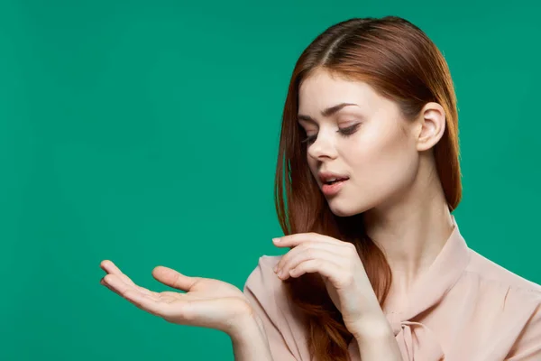 Mulher bonita alegre em uma camisa rosa segura a mão na frente de suas emoções Fundo verde — Fotografia de Stock