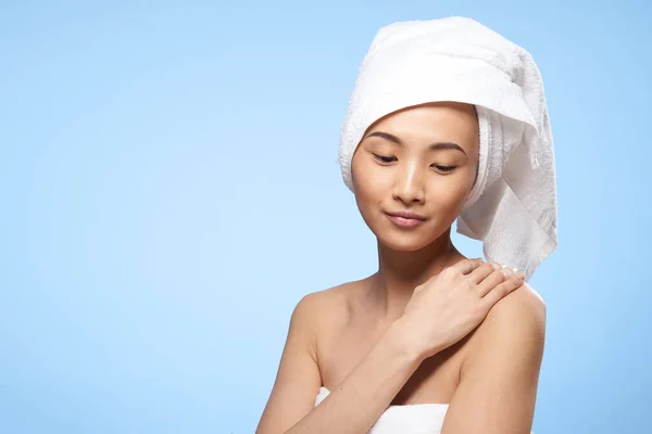 Mooie vrouw aziatische verschijning kale schouders handdoek op hoofd spa procedure blauw achtergrond — Stockfoto