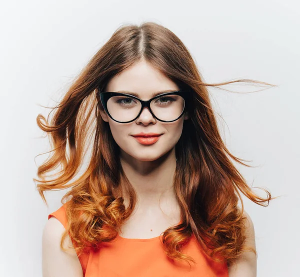 attractive woman with loose hair and glasses and an orange sundress