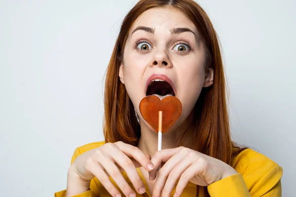 Attractive woman licking lollipop yellow shirt emotions close-up — Stock Photo, Image
