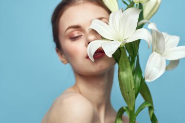 Mavi arka planda beyaz çiçekli bir kadın çıplak omuzları kesiyordu.