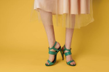 Şık ayakkabılar, yeşil ayakkabılar, kadın ayaklar, sarı arka plan.