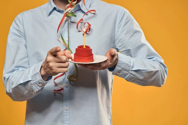 Guy with a cake in a plate on a yellow background holidays gyertya vágott kilátás — Stock Fotó