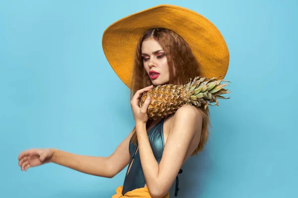 Kvinna i strand hatt ananas innehav baddräkt exotiska frukter blå bakgrund semester — Stockfoto