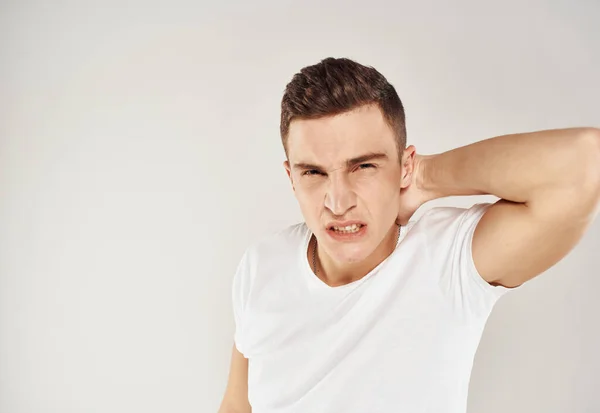 Un gars dans un T-shirt blanc émotions irritabilité lumière fond état inadéquat — Photo