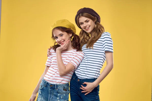 funny mom and daughter wearing hats fashion fun joy family yellow background