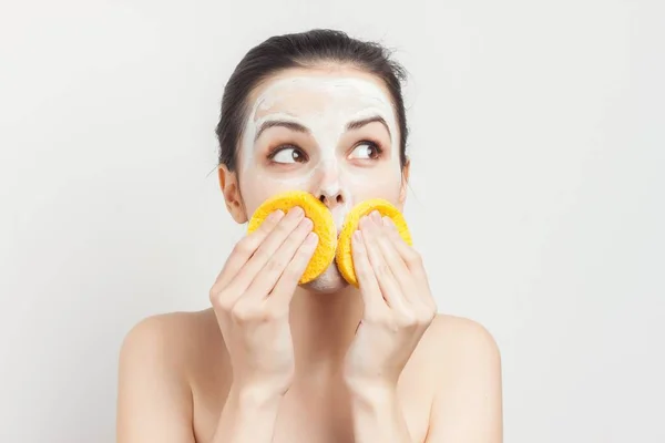 Fröhlich Brünette wischt Gesichtsmaske mit Schwämmen abgeschnitten Ansicht — Stockfoto