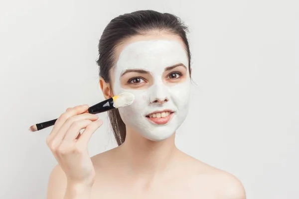 Jolie femme aux épaules nues appliquer brosse à crème pour les soins du visage spa — Photo