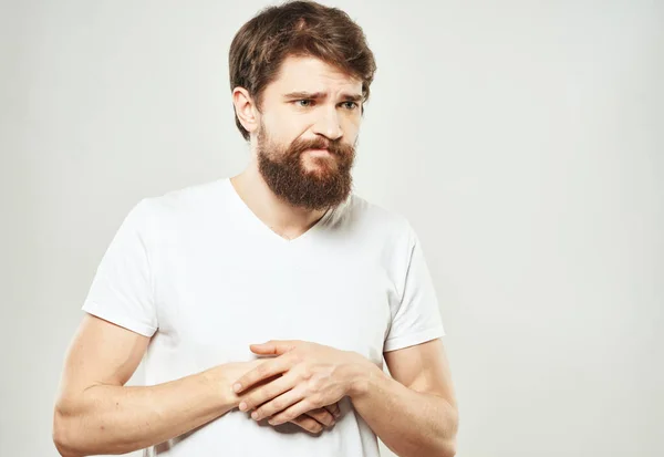 Guy i en vit T-shirt på en ljus bakgrund känslor sorgligt ansikte beskärd vy — Stockfoto