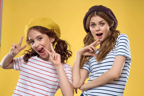 funny mom and daughter wearing hats fashion fun joy family yellow background