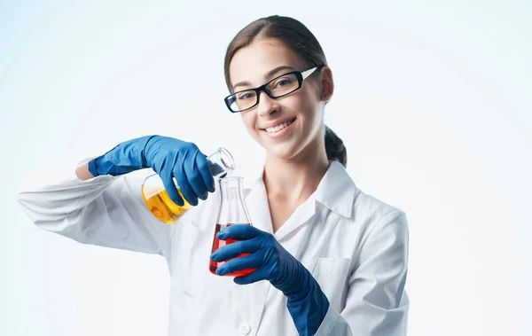 Un infermiere in camice da laboratorio e guanti blu con una fiaschetta in mano elemento chimico laboratorio analizza — Foto Stock