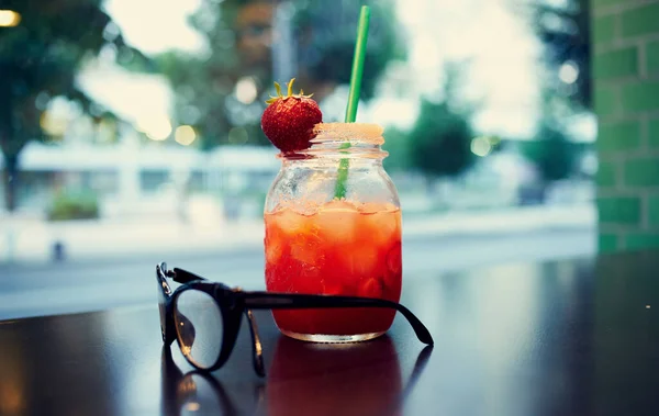 Glas met een drankje in een vrouwenhand en café — Stockfoto
