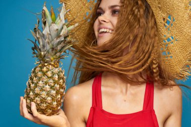 Elinde ananas olan hasır şapkalı bir kadın mı yoksa egzotik, eğlenceli bir meyve arka planı mı?