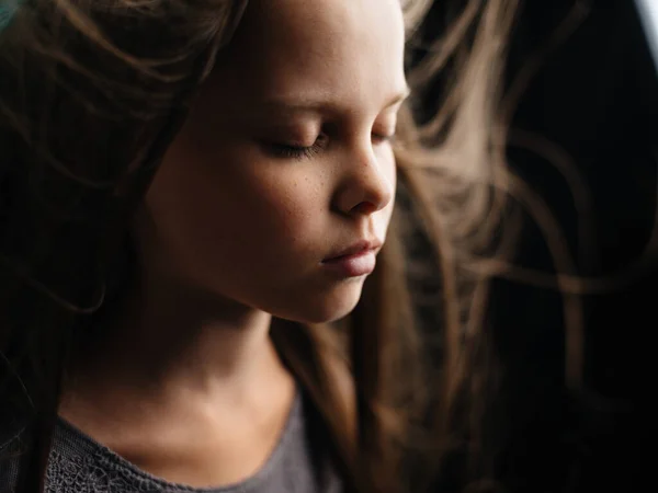 Retrato de uma menina bonita com olhos fechados em um fundo turquesa e cabelo solto close-up corte vista. — Fotografia de Stock