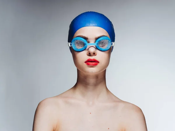 Mavi yüzme şapkalı ve gri arka planda gözlüklü bir kadının ön görüntüsü. — Stok fotoğraf
