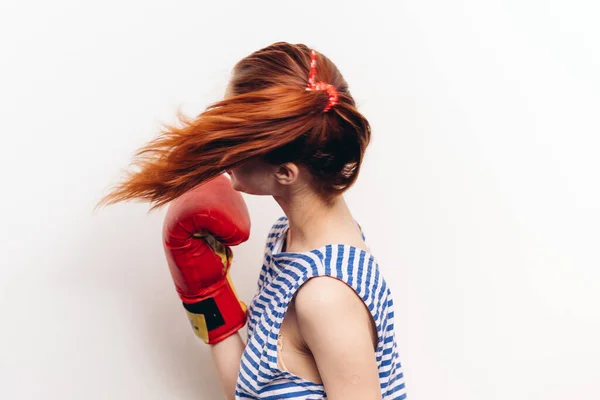 Vrouw oefenen van een klap in bokshandschoenen op een lichte achtergrond gestreepte t-shirt model — Stockfoto