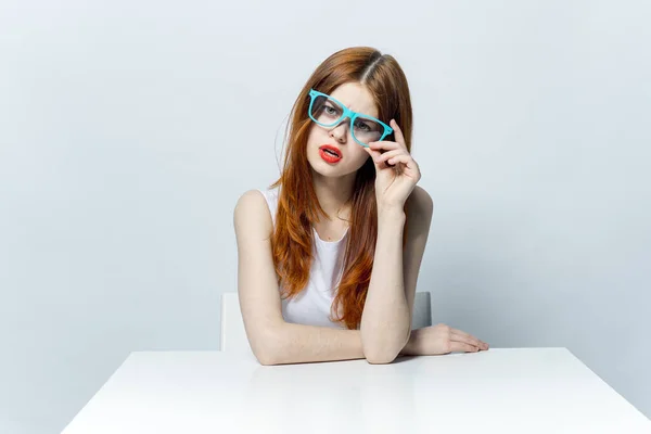 Pretty woman in blue glasses sitting at the table red lips smile attractive look — Stock Photo, Image