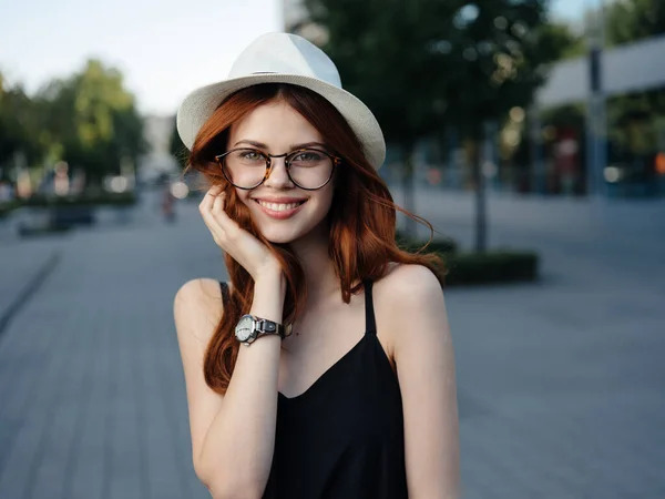Attraktiv kvinna promenader på gatan bär hatt och glasögon — Stockfoto