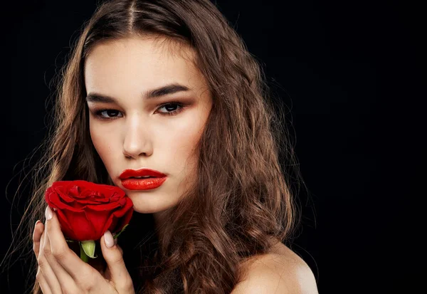 Barna nő piros rózsával a kezében egy sötét háttér közelkép — Stock Fotó