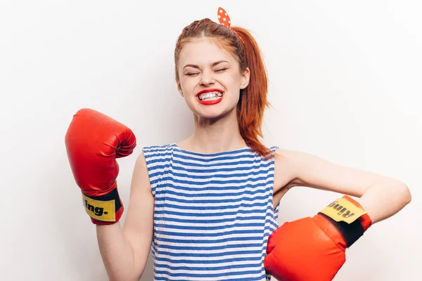 Femme aux cheveux roux en gants de boxe et un t-shirt rayé sur fond clair avec une bouche ouverte — Photo