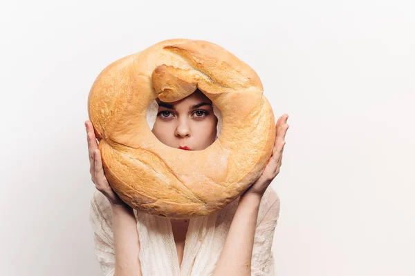 Bela mulher com um pão redondo em suas mãos em um modelo de maquiagem de produto de farinha de fundo leve — Fotografia de Stock