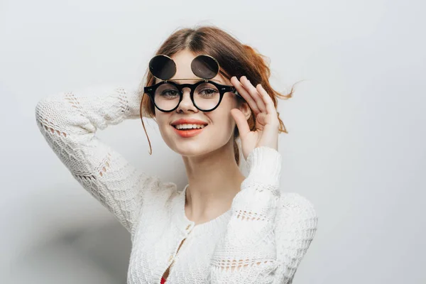 Vrouw in witte trui trendy bril moderne stijl bijgesneden look en lichte achtergrond — Stockfoto
