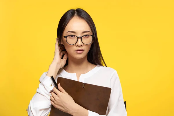 Obchodní žena v brýlích s poznámkovým blokem v ruce výkonný tajemník žluté pozadí — Stock fotografie
