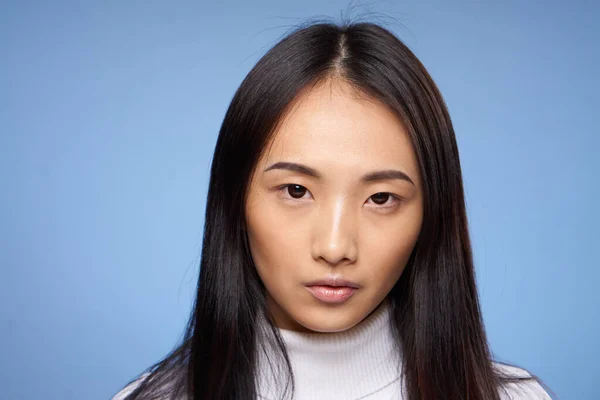 Kvinna asiatisk utseende vit tröja beskärd vy blå bakgrund — Stockfoto