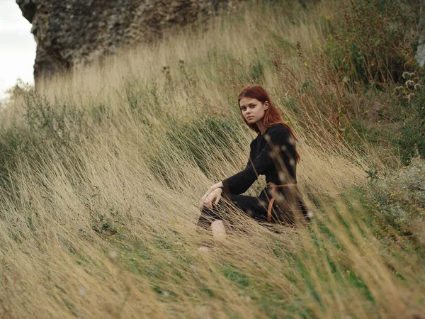 Kadın sonbaharda ormandaki kuru çimlerde oturur. — Stok fotoğraf