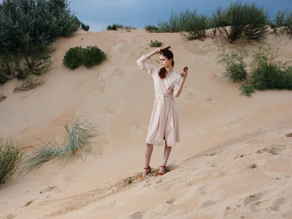 Romantische vrouw met een kam in een witte zonnejurk en rode schoenen staat op het zand — Stockfoto