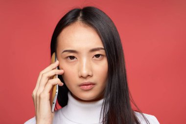 Güzel esmer, telefon teknolojisiyle konuşuyor. Yakın plan kırmızı arka plan.
