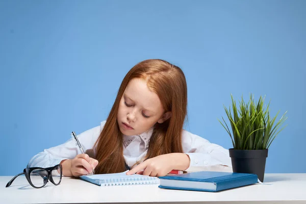 テーブルスクールの教科教育で宿題をしている赤髪の女の子は — ストック写真