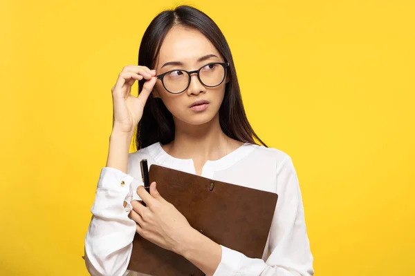 Donna d'affari in occhiali con blocco note in mano segretario esecutivo sfondo giallo — Foto Stock