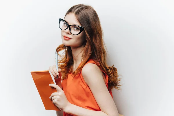 Mulher de cabelos vermelhos na camisa com notepad charme óculos moda luz fundo — Fotografia de Stock