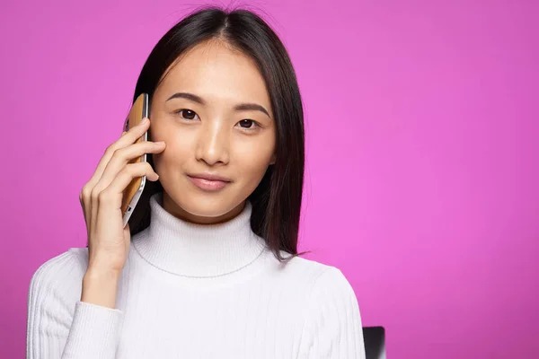 Женщина азиатской внешности говорить по телефону технологии образ жизни розовый фон — стоковое фото