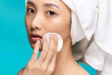 Asyalı kadın yüz havlusuyla baş derisi bakım spa prosedürlerini kapatıyor.