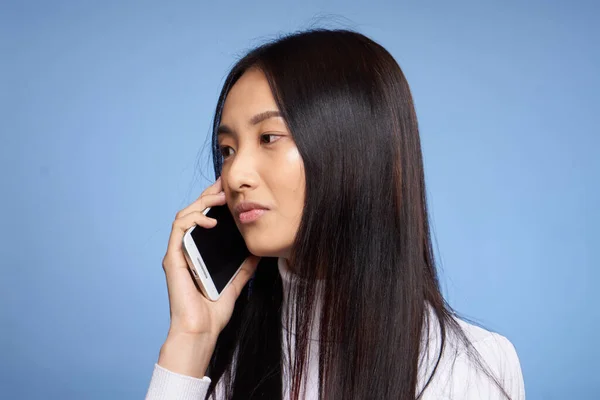 Asiática mujer extremidades hablando por teléfono en azul fondo estudio — Foto de Stock
