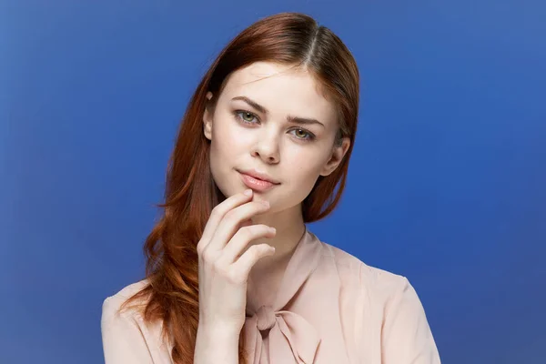 Mulher bonita na mão camisa rosa perto do rosto azul fundo — Fotografia de Stock