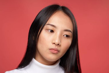 Güzel kadın Asyalı görünüşü beyaz süveter duyguları kırmızı arka plan