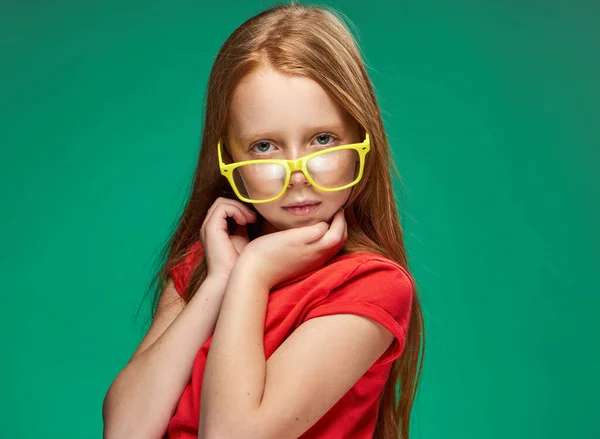 Chica emocional con el pelo rojo usando gafas amarillas escuela aislado fondo — Foto de Stock