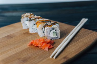 Sushi kırmızı zencefilli çubukları yuvarlıyor tahta tahtaya yakın plan