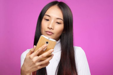 Elinde telefon olan güzel bir kadın ekrandaki internet iletişim teknolojisine bakıyor.