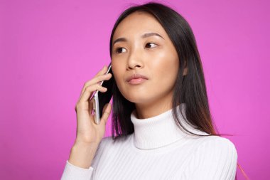Asyalı kadın telefonda konuşuyor. Hayat tarzı teknoloji pembe arka plan stüdyosu.
