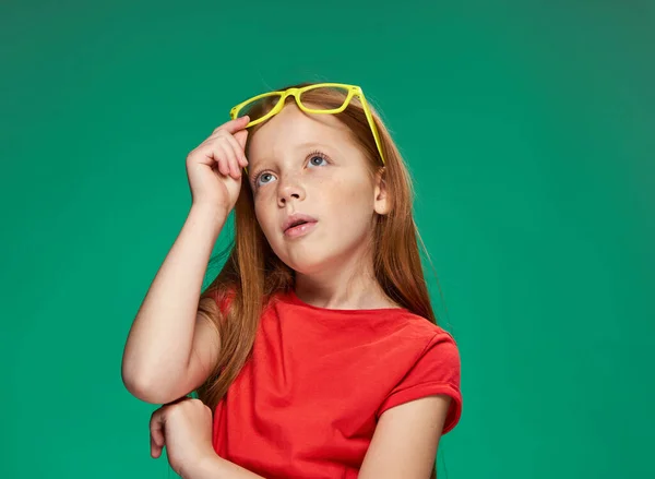 Emotivní dívka s červenými vlasy nosí žluté brýle škola izolované pozadí — Stock fotografie